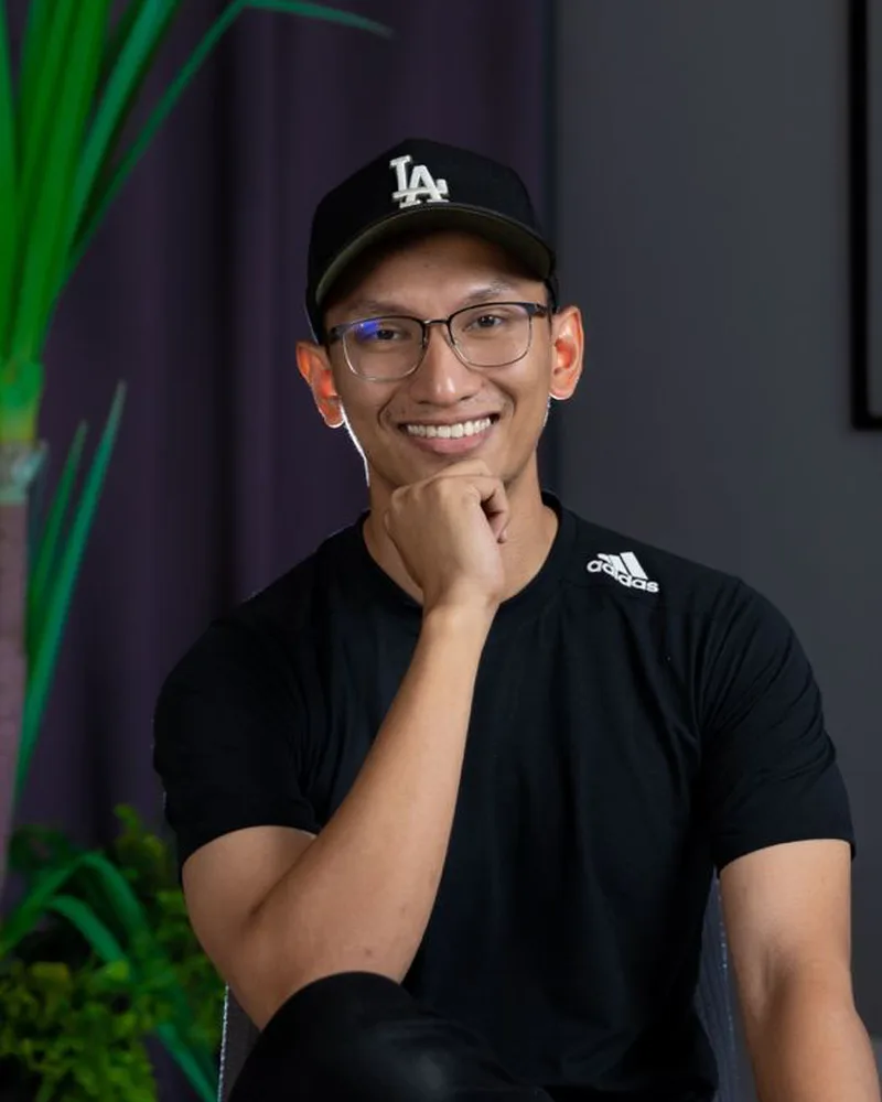 Huzaifah Za'ba, smiling, in a black cap and black T-shirt